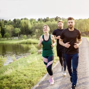 Group of friends jogging during the morning exercise in the park near the lake