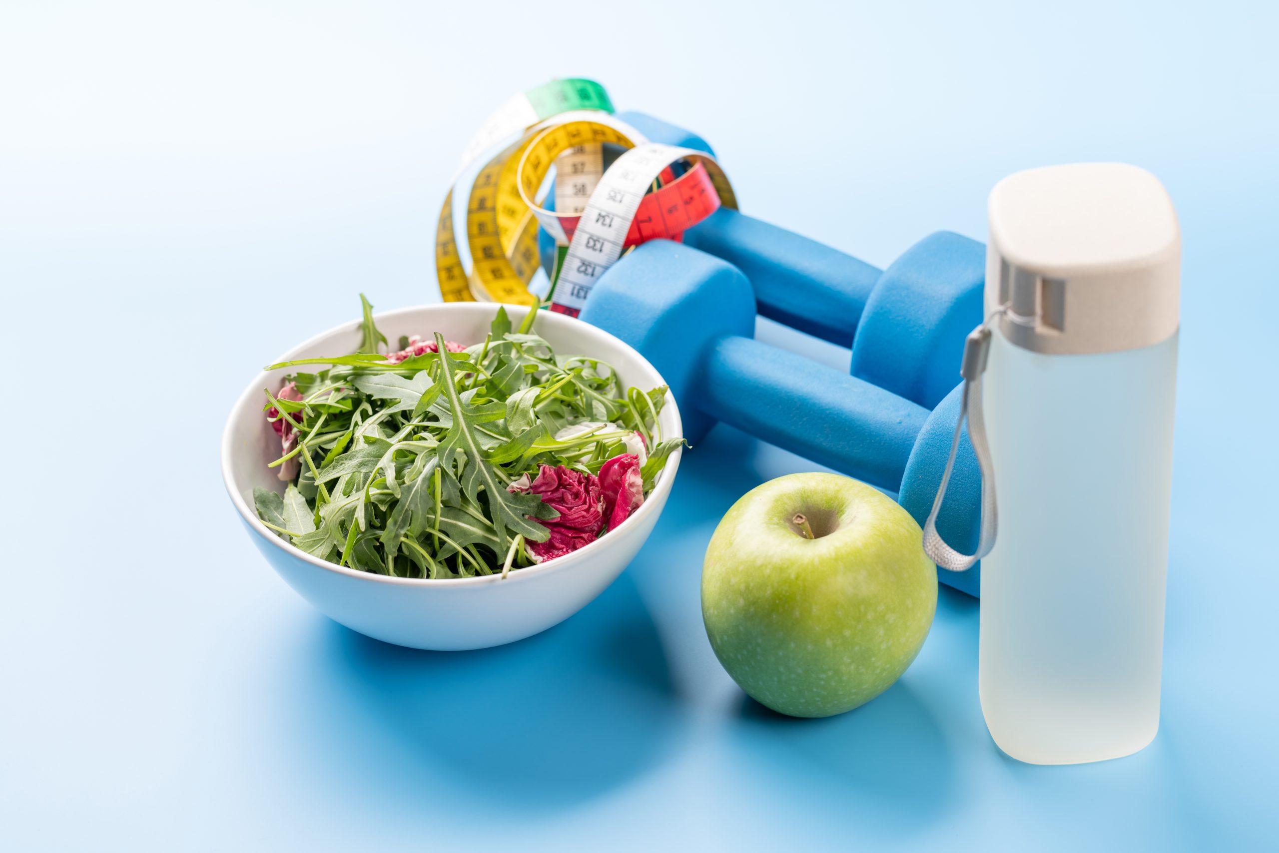 Gezonde voeding, sportmaterialen en een drinkfles op een blauwe achtergrond