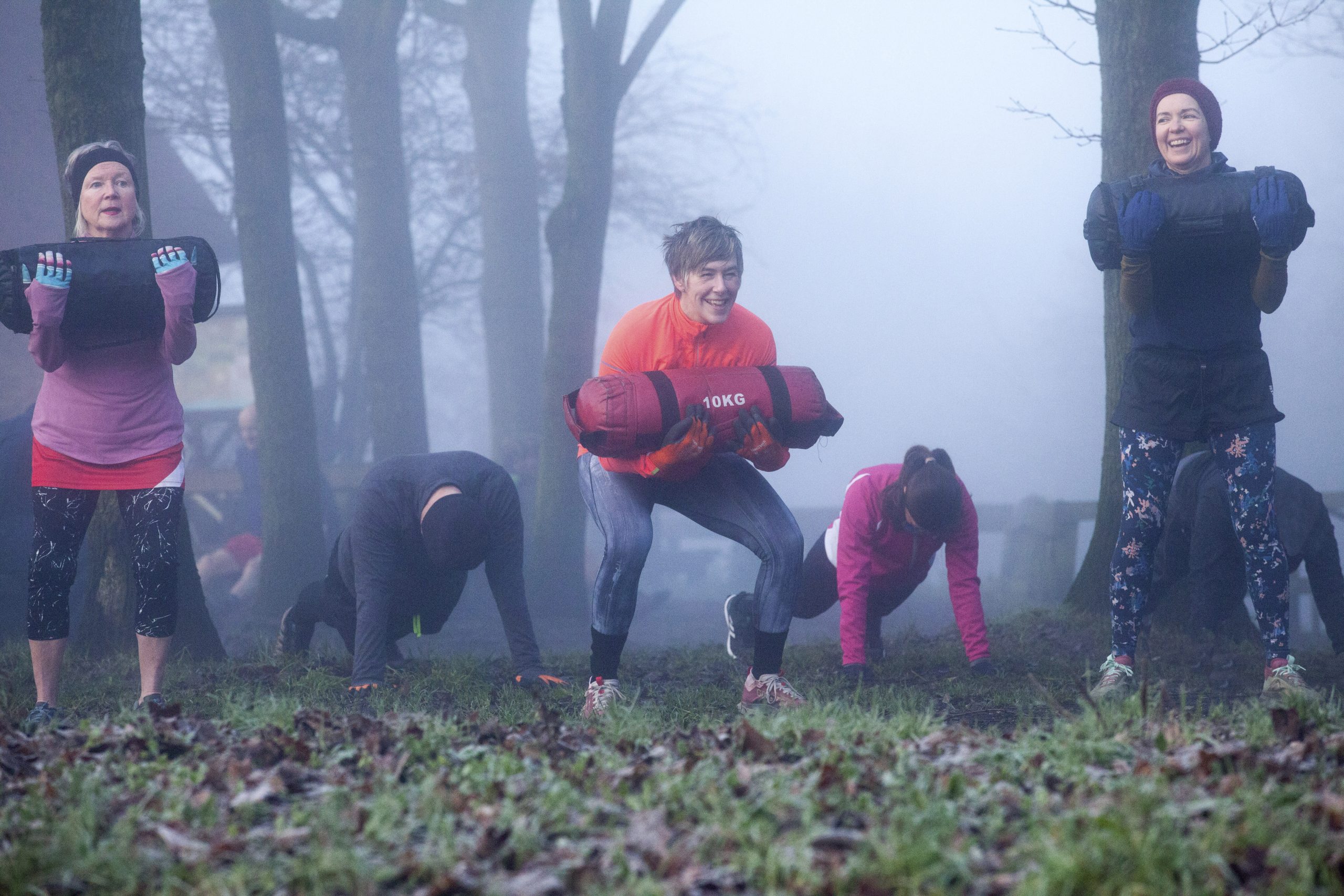 Een groep volwassenen traint samen buiten in de mist